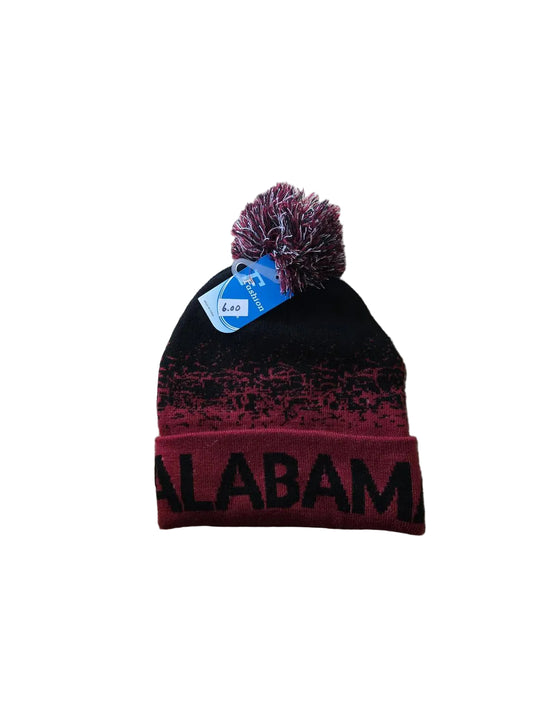 Black and red beanie with 'Alabama' text and purple pom-pom on a beige carpet

