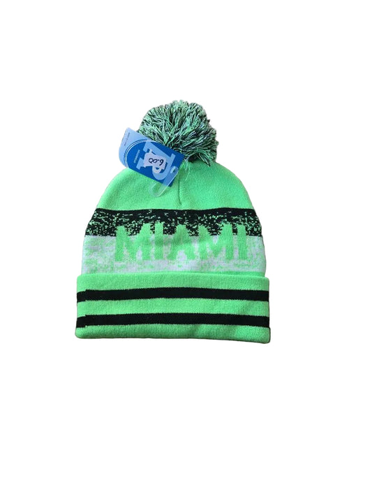 Green beanie with black stripes and a pom-pom on a brown carpet

