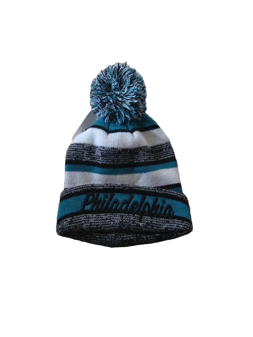 Striped beanie with pom-pom on a brown carpet

